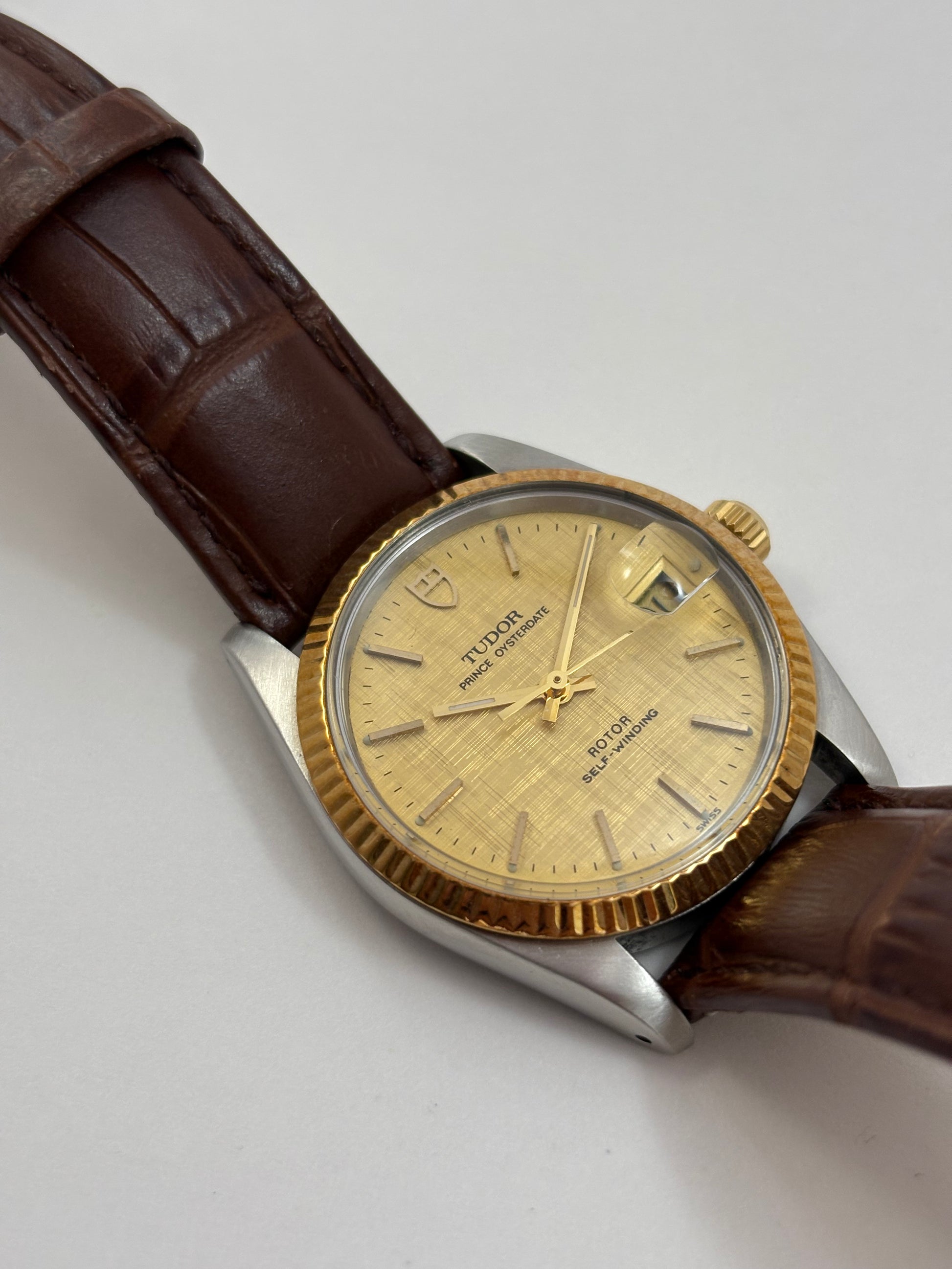 Vintage watch with brown leather strap and gold-dial face on a light gray background