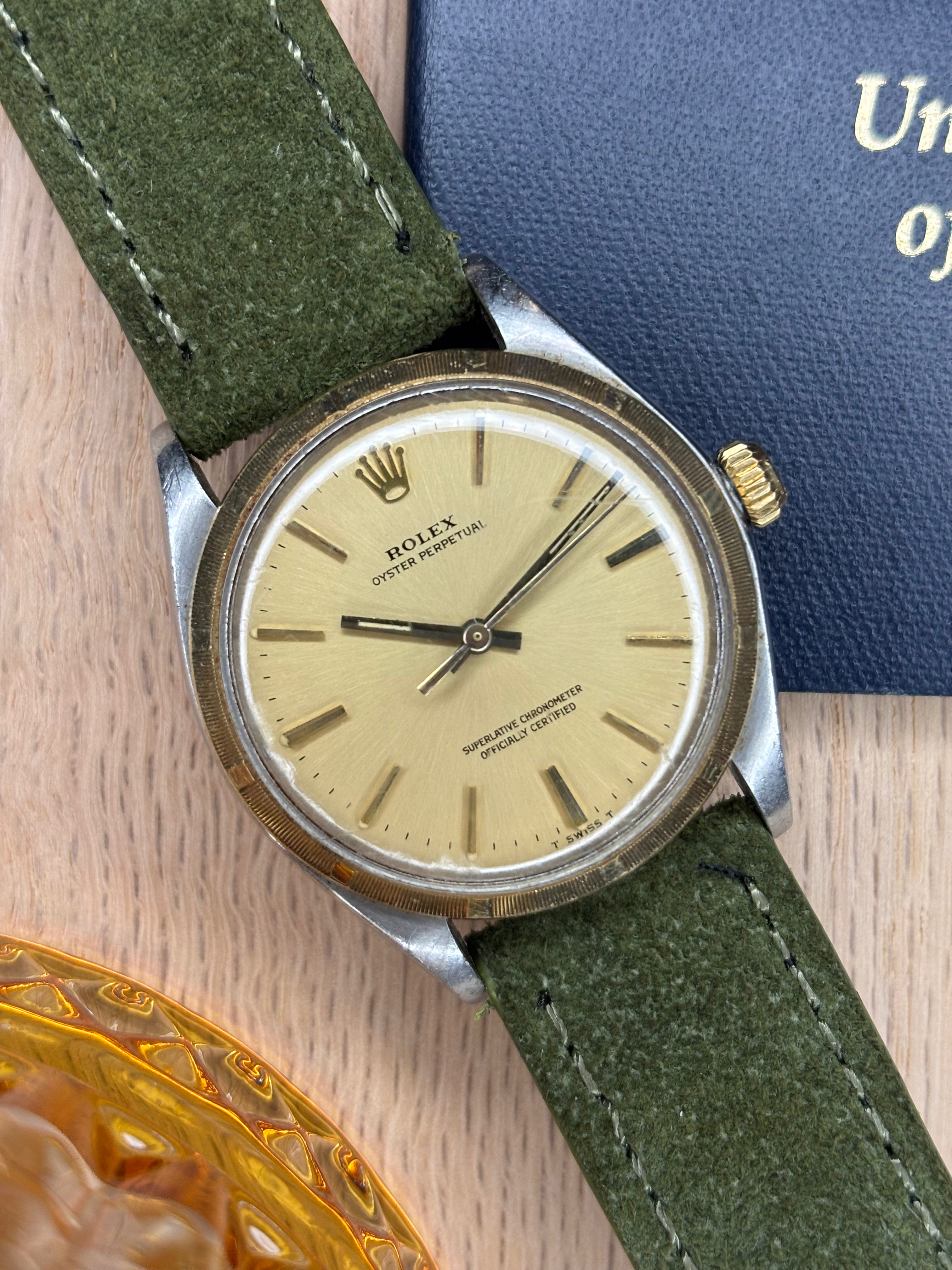 Vintage Rolex watch with green strap on a wooden surface with a passport and whiskey