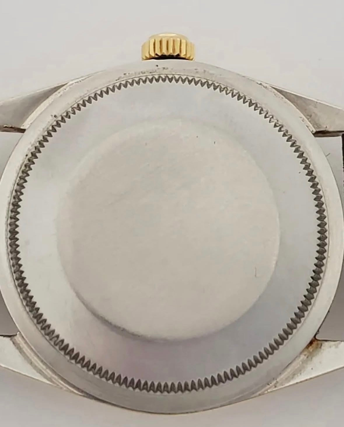 Close up of a watch case with a gold bezel and silver metal casing on a white background